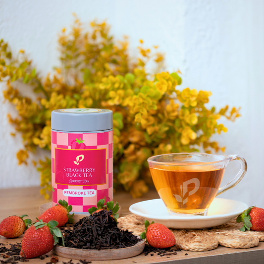 Pembroke tea's Strawberry Black Tea with a cup of brewed tea, strawberries, and tea leaves 